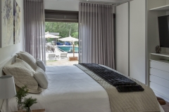 - Trabalhado com tons de branco, o quarto ganhou um destaque com a mesa de cabeceira em tom terroso. A madeira sempre traz um aconchego a mais para os ambientes